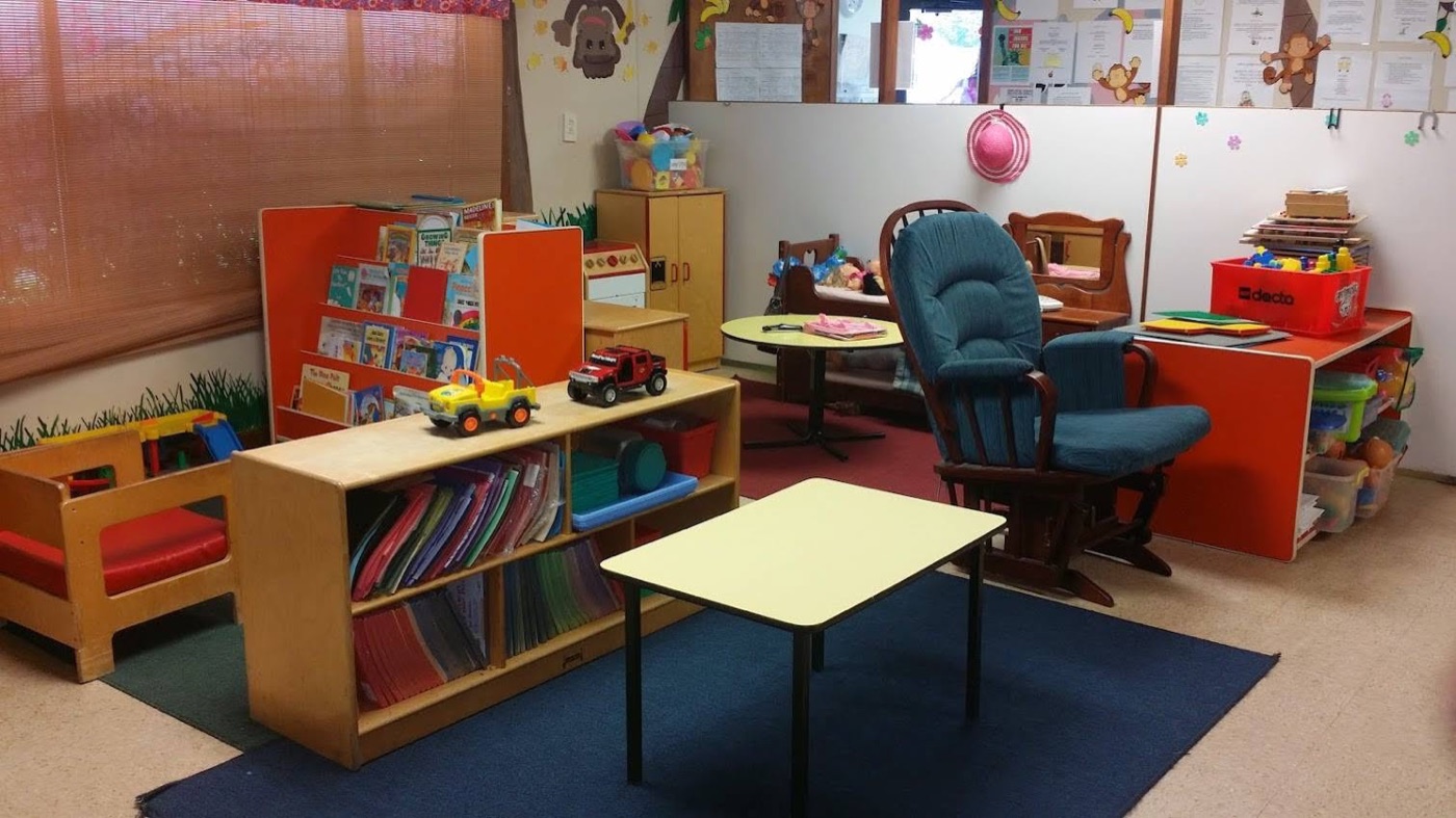 Bright classroom with bookshelves, toys, and child-sized furniture at Village Childcare