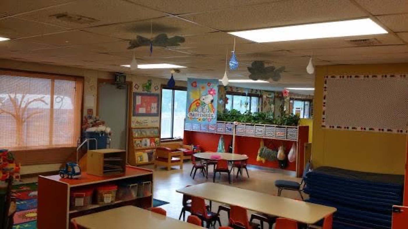 Spacious activity room with tables, chairs, and hanging classroom decorations